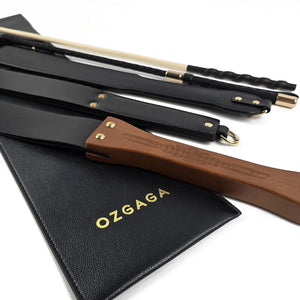 Deluxe BDSM Punisher Spanking Kit featuring impact play tools including a riding crop, spanking cane, leather paddle ruler, triple-layered spanking paddle, and a wooden-handle leather paddle, displayed with a black leather storage bag.
