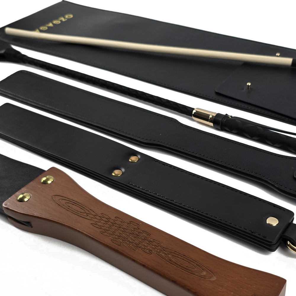 Deluxe BDSM Punisher Spanking Kit featuring impact play tools including a riding crop, spanking cane, leather paddle ruler, triple-layered spanking paddle, and a wooden-handle leather paddle, displayed with a black leather storage bag.