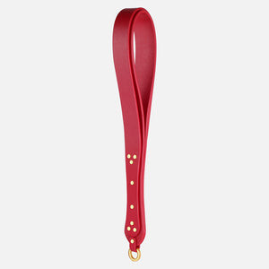 Red leather spanking paddle with gold hardware on a white background