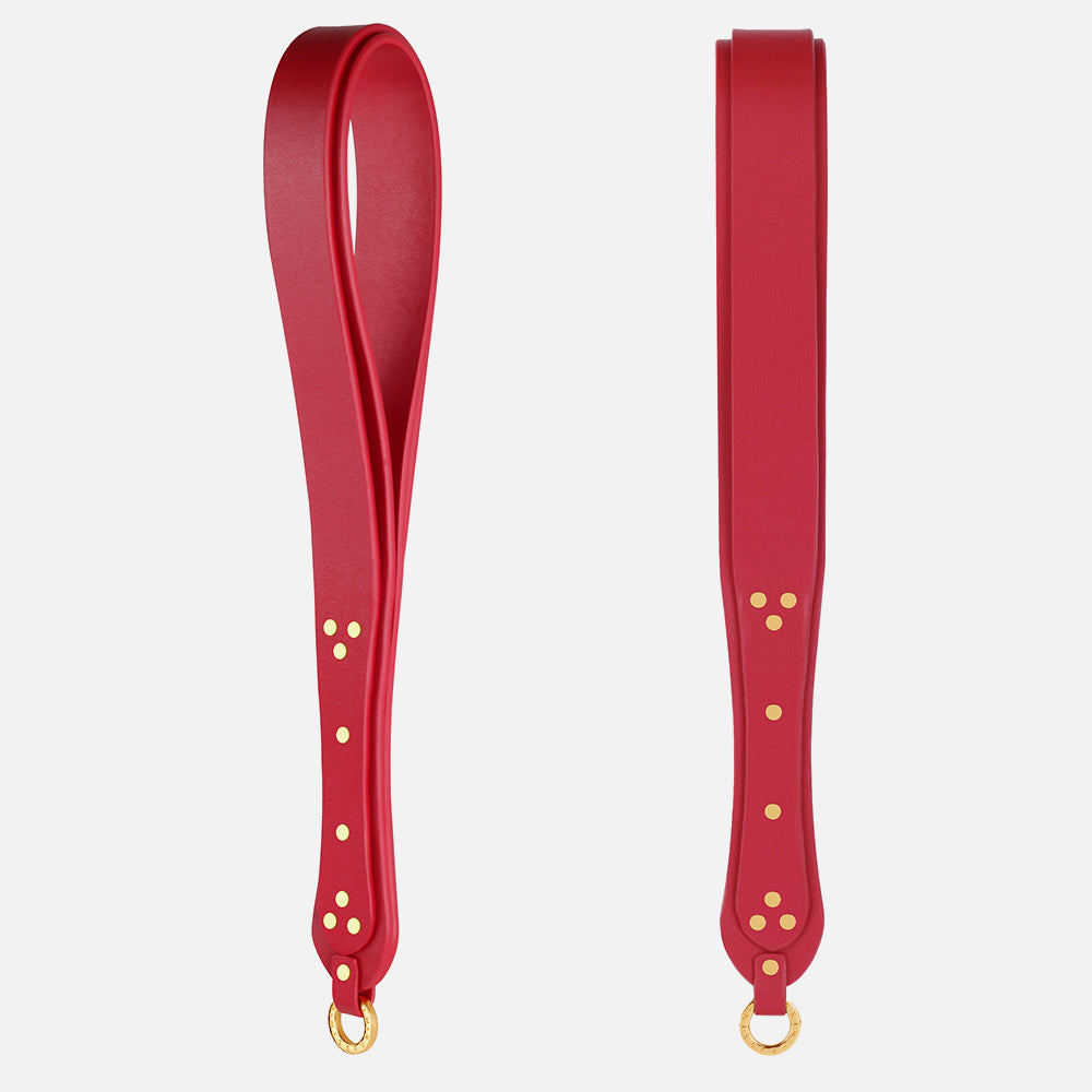 Red leather spanking paddle with gold hardware on a white background