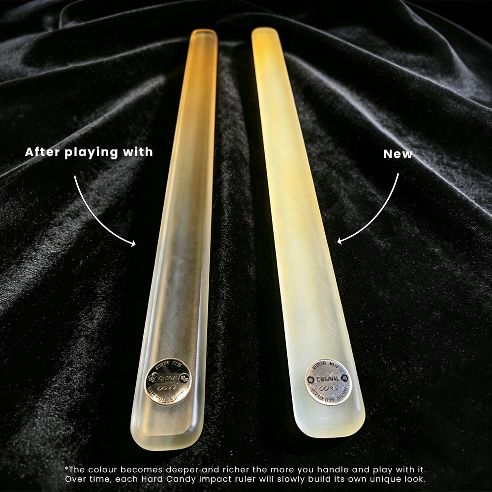 Two translucent hard candy impact rulers on a black velvet background, with text labels 'After playing with' and 'Now' showing color change over time. The left ruler is clear, and the right ruler is yellowed due to handling and play.
