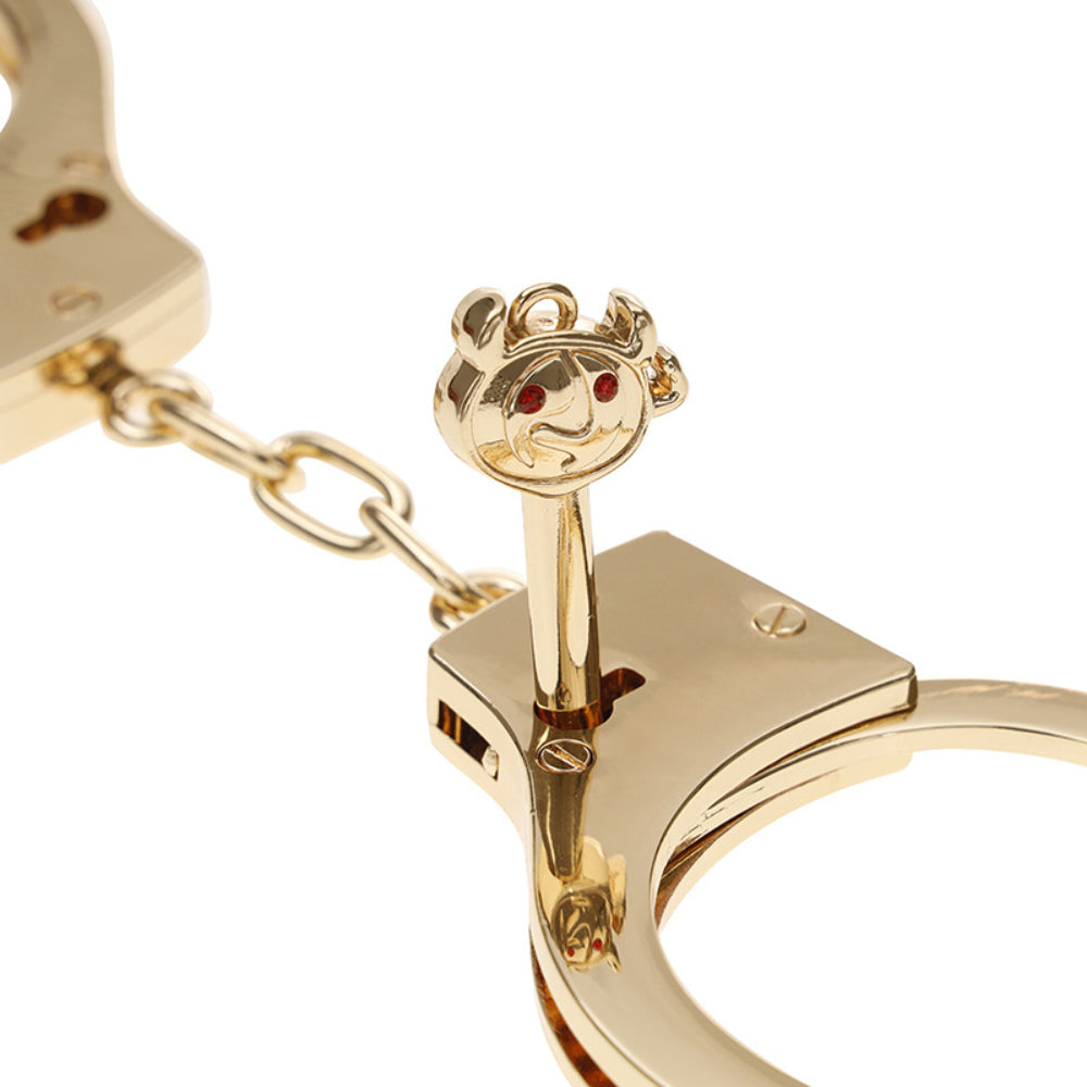 Gold stainless steel handcuffs with safety release and keys, designed for BDSM play, featuring a sleek and durable design.